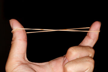 An elastic band stretched between a finger and thumb
