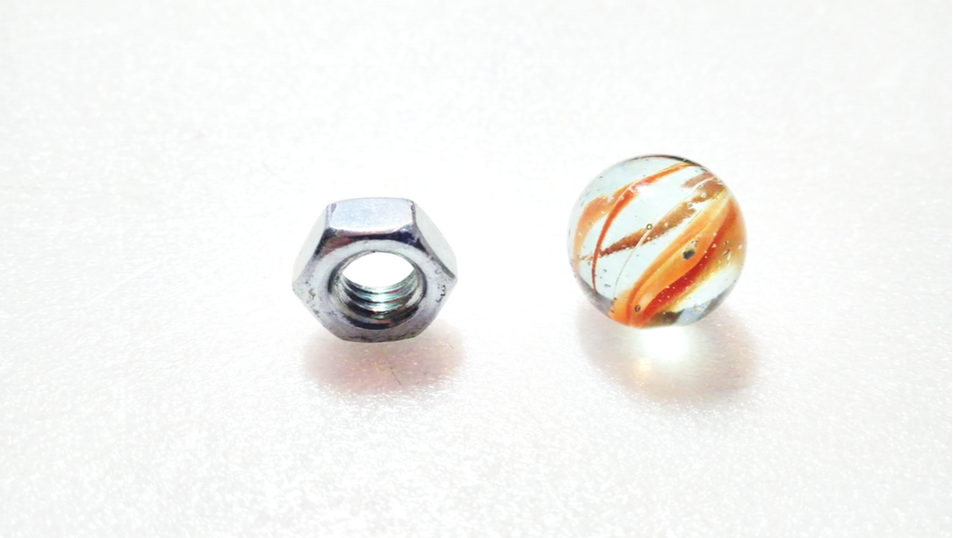A steel hex nut and a glass marble